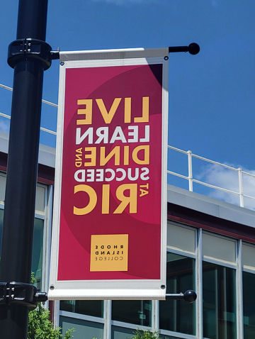 Dining banner, saying Live, Learn, Dine and Succeed at RIC, flying on campus